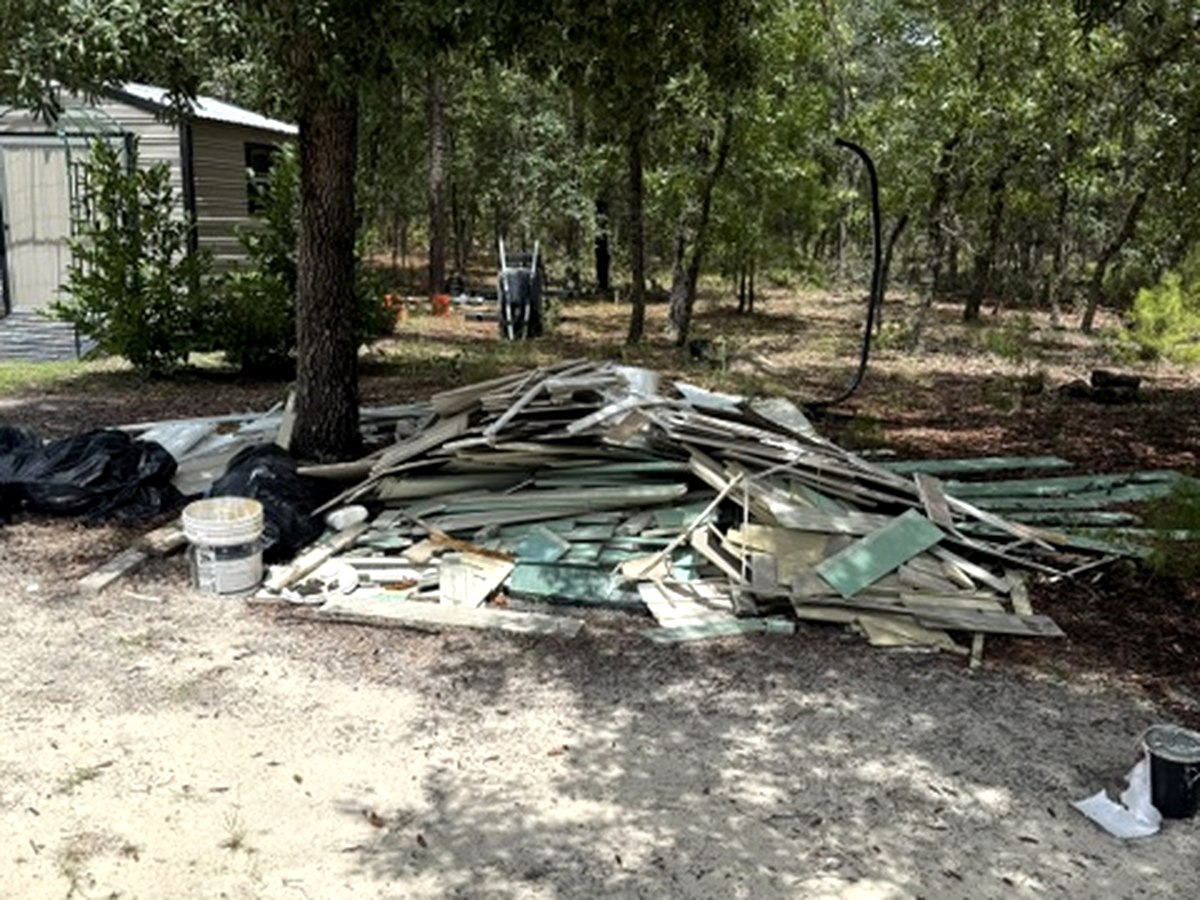 Demolition and siding debris piled before Backroad Hauling cleanout